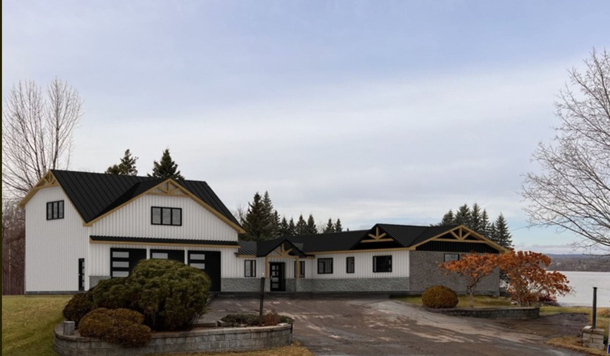 Modélisation 3D d'une maison au revêtement blanc et à la toiture métallique noire, avec garage triple