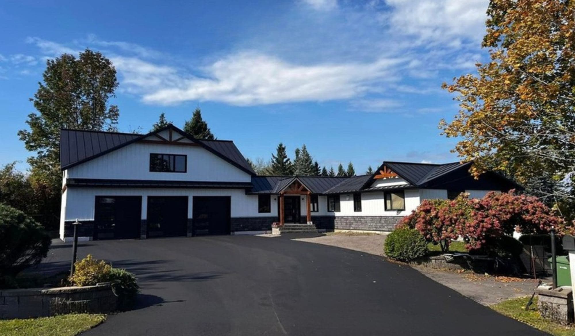 Maison agrandie et rénovée : revêtement blanc, toiture métallique noire et garage triple