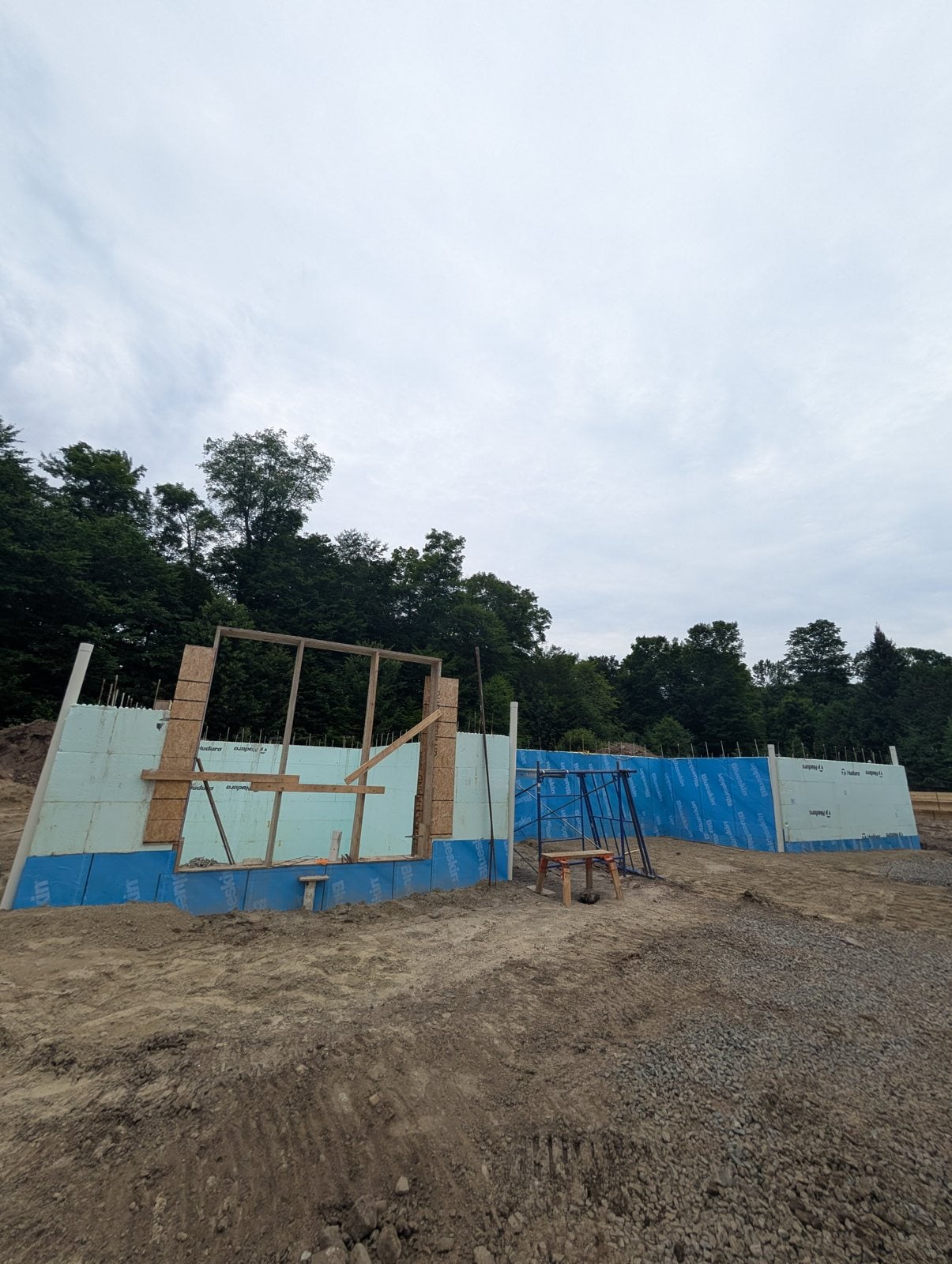 Murs en blocs isolants montés sur la fondation, avec le cadre d'une grande ouverture et une membrane bleue