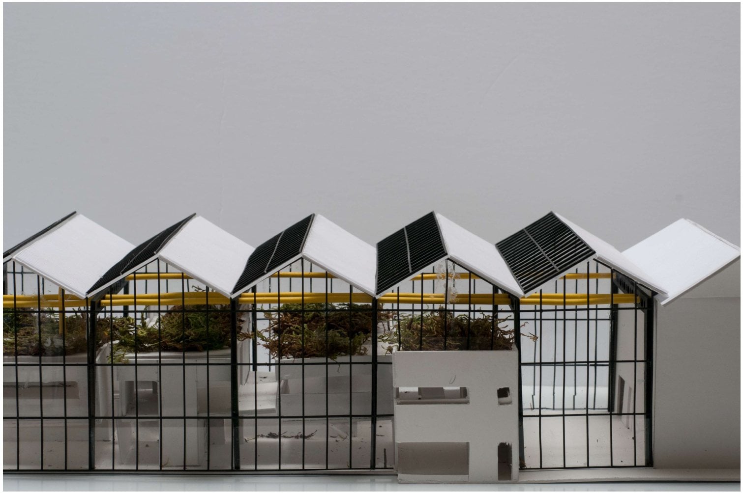 Maquette de la coopérative Rivière-des-Prairies : des habitations sous trois serres vitrées aux toits en dents de scie, avec une tuyauterie jaune