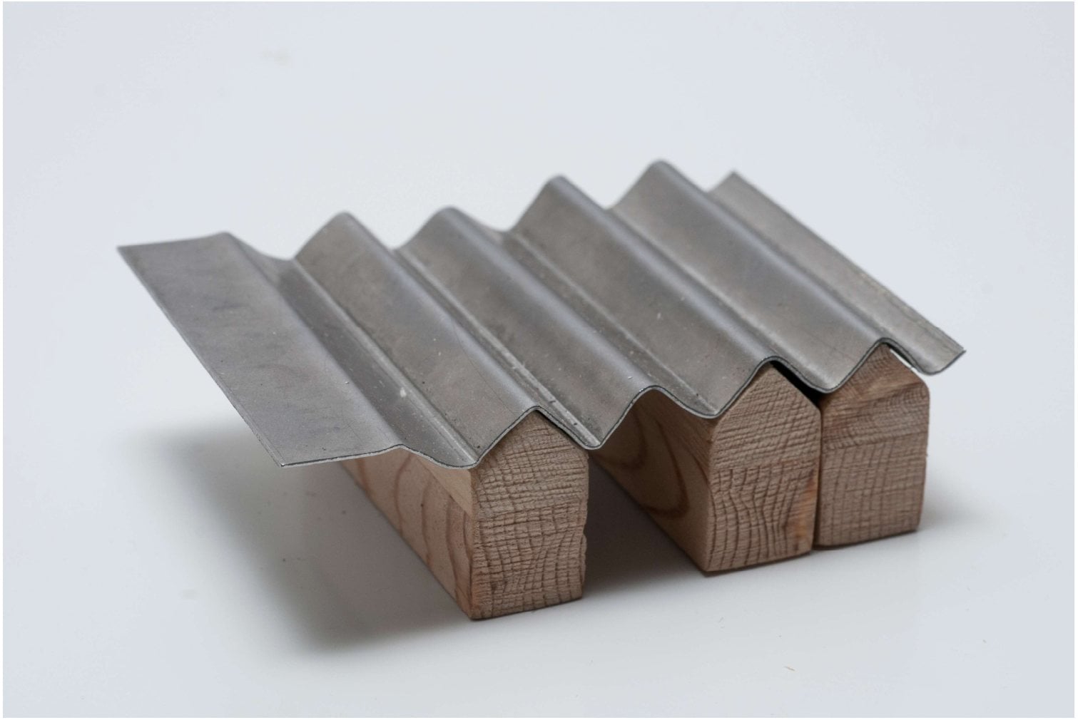 Objet synthèse : trois petites maisons en bois coiffées d'une tôle ondulée