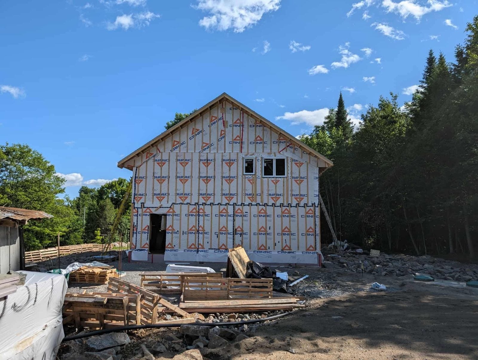 Charpente de la maison recouverte de pare-air, avec les fenêtres installées
