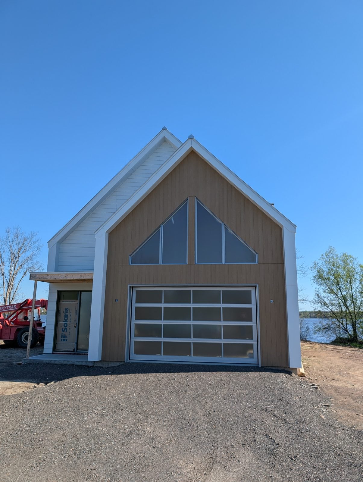 Photo de la maison construite : pignon vitré et revêtu de bois, porte de garage vitrée