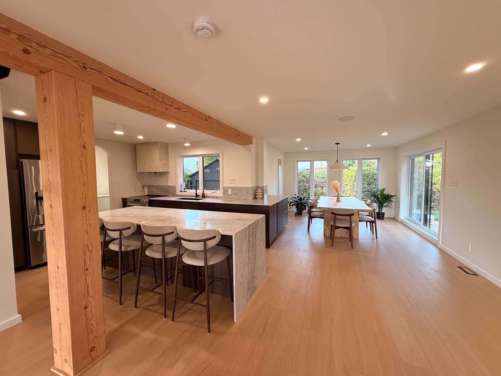 After the work: stone kitchen island, wood beam and post, large open-plan room