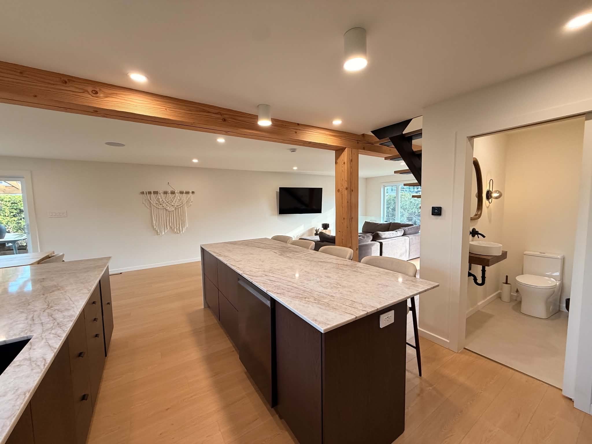 After the work: kitchen island and powder room with a vessel sink and rounded mirror