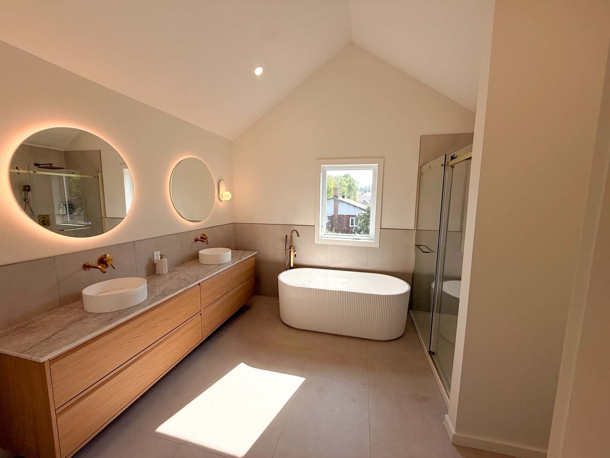 After the work: bathroom under a cathedral ceiling, double vanity, freestanding tub and glass shower