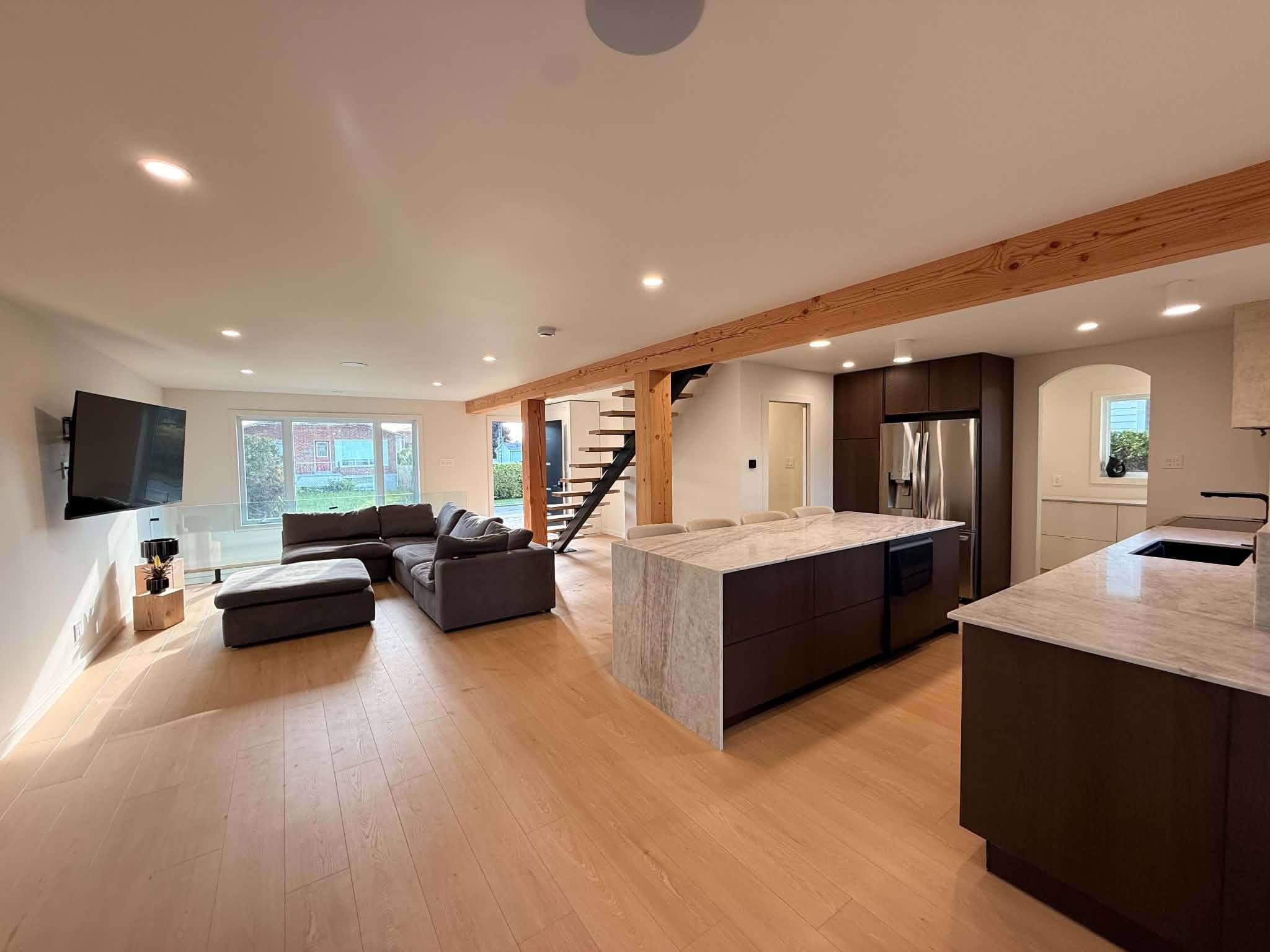 After the work: open-plan living room and kitchen, light wood floor and steel-stringer staircase