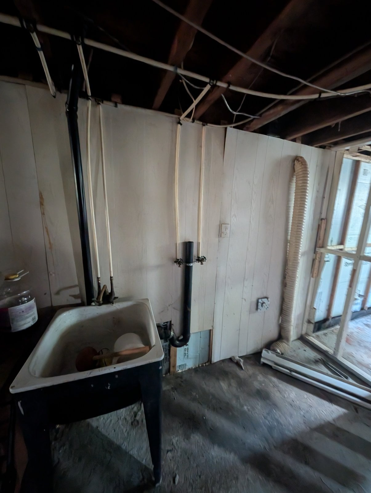 Basement before the work: the laundry area, wider view, with wood paneling on the walls