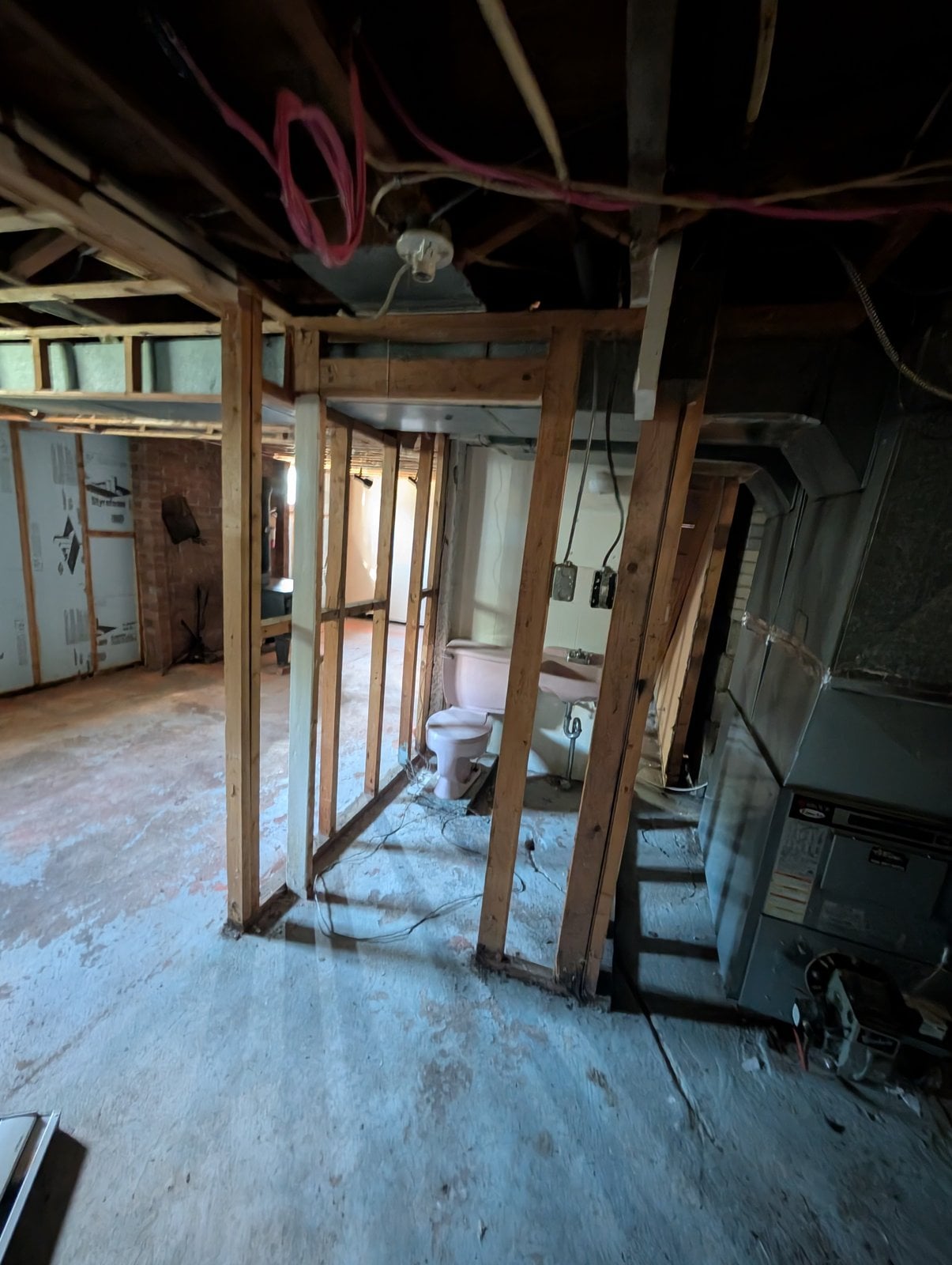 Basement before the work: partition framing and the original pink toilet