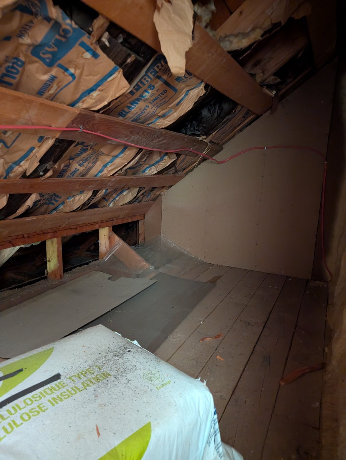 Attic before the work: insulation batts under the roof and a plank floor