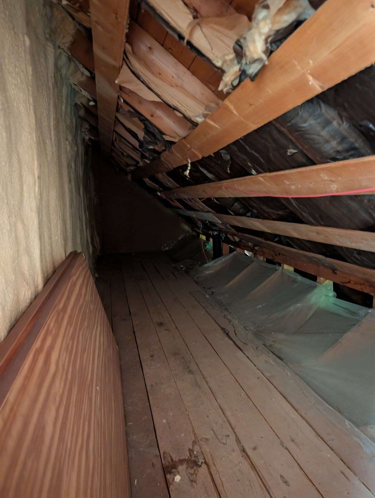 Narrow passage in the attic before the work, with spray foam on one wall