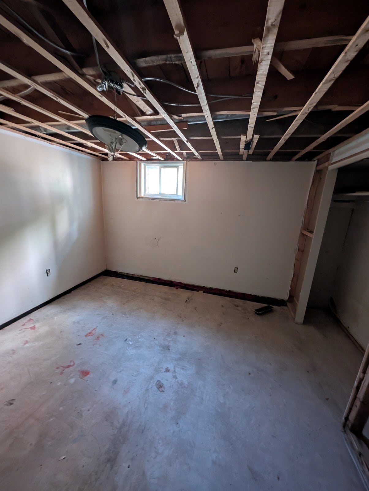 Basement room before the work, with its small window and raw floor