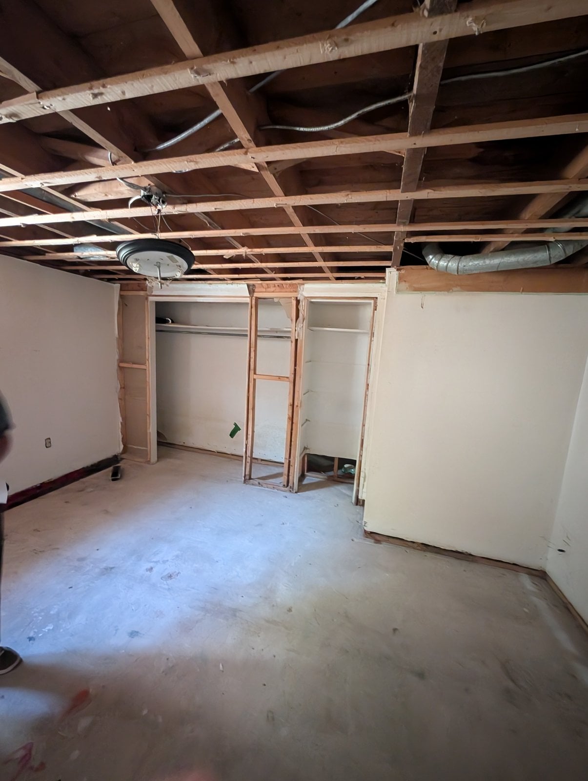 Basement room before the work: open ceiling and stripped-out closets