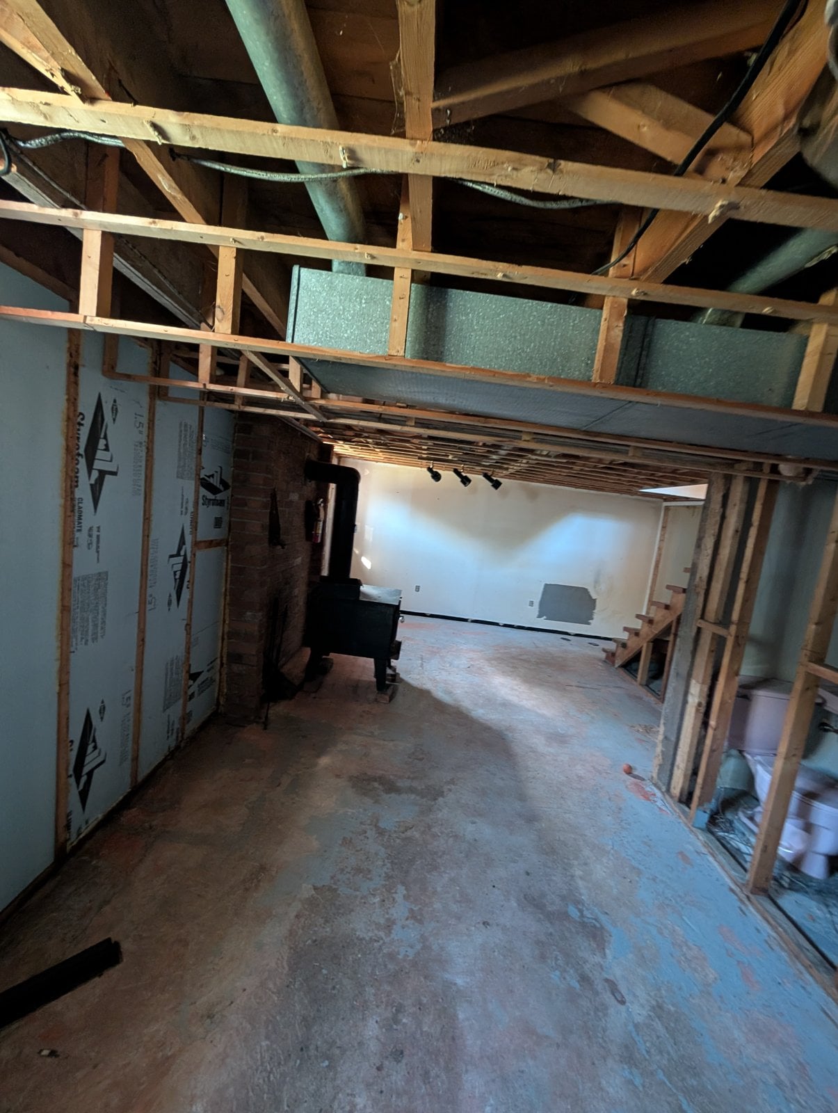Basement before the work: wood stove, brick wall and bare partitions
