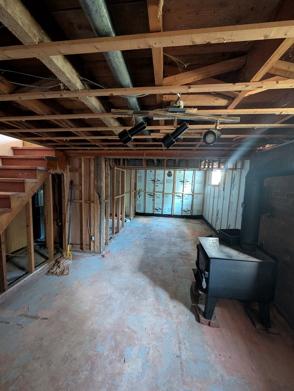 Basement before the work: wood stove, brick wall and walls insulated with rigid foam