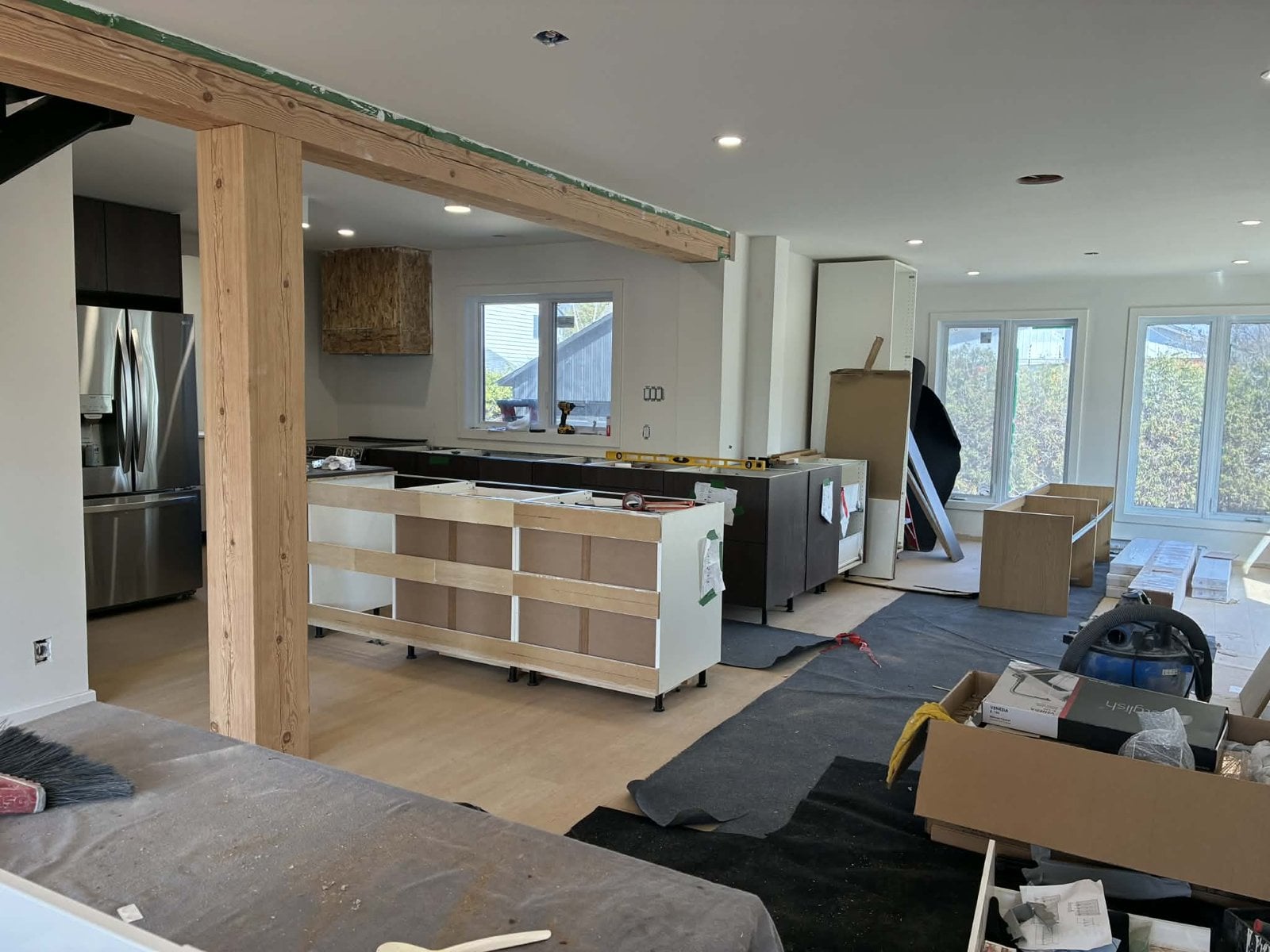 During the work: kitchen cabinets being installed under the exposed wood beam