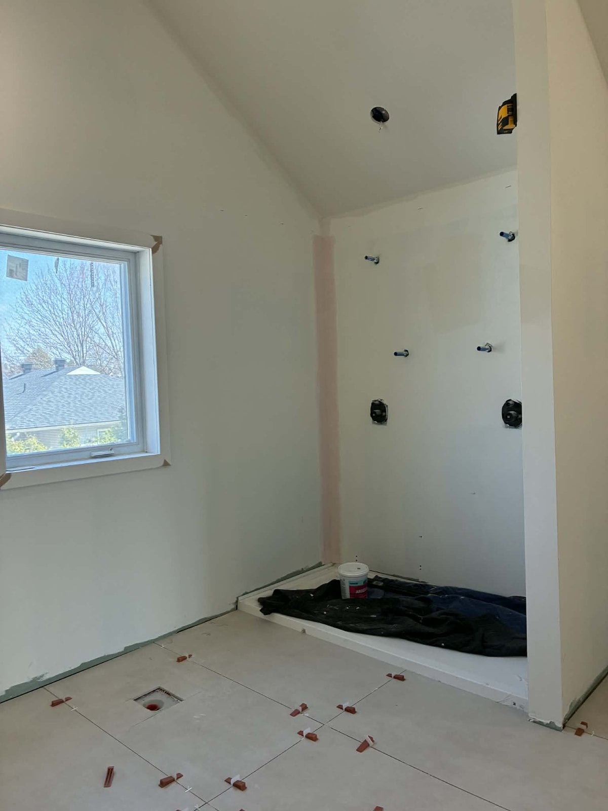 During the work: shower being prepared, with rough-in valves and floor tiles being laid