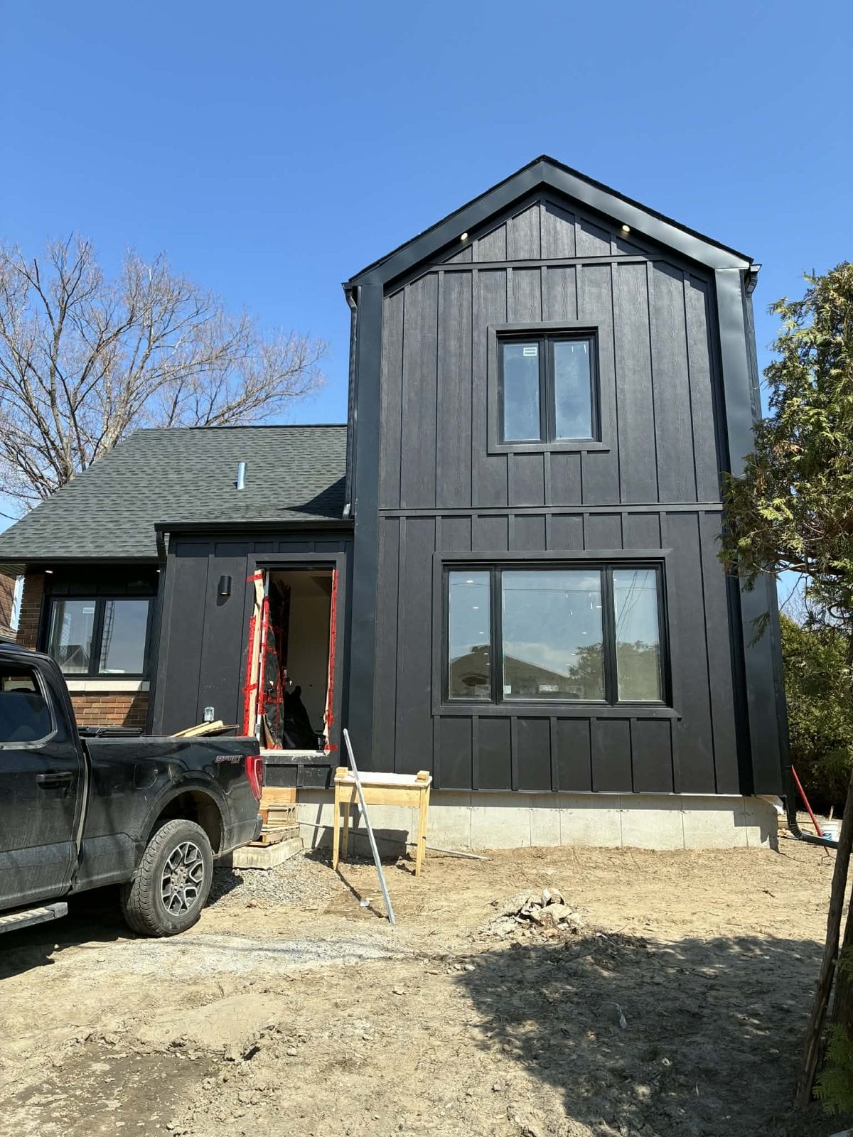 During the work: addition front clad in black vertical boards, next to the original brick