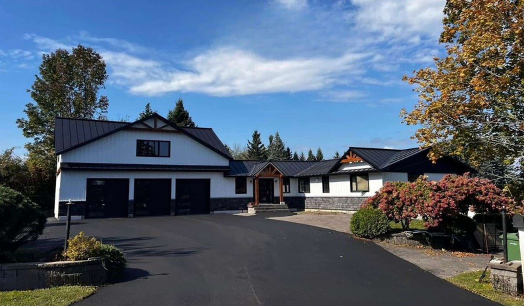 Maison agrandie et rénovée : revêtement blanc, toiture métallique noire et garage triple
